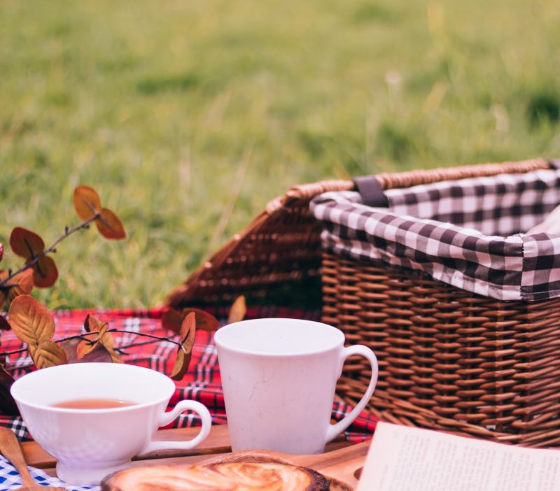 picnic basket with a cup of tea standing besides it.